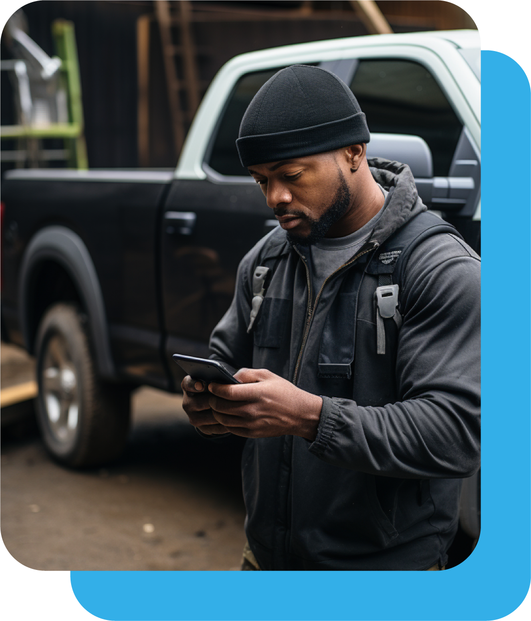 Contractor standing in front of pickup truck sending text message on phone